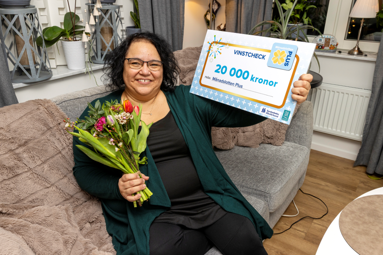 Vinnare sitter i fåtölj med vinstcheck