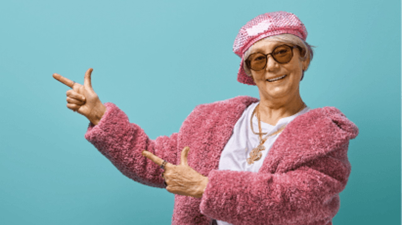 Kvinna i rosa outfit poserar glatt.