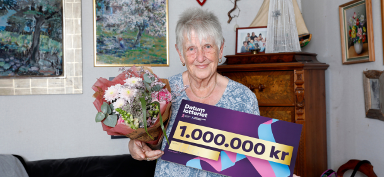 Vinnare med blommor och vinstcheck på 1 000 000 kr i sitt hem