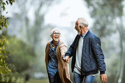 Äldre par promenerar hand i hand utomhus