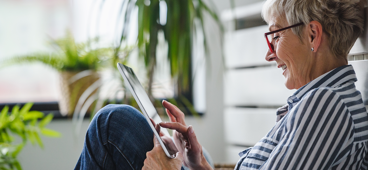 Leende kvinna som håller på med sin surfplatta.