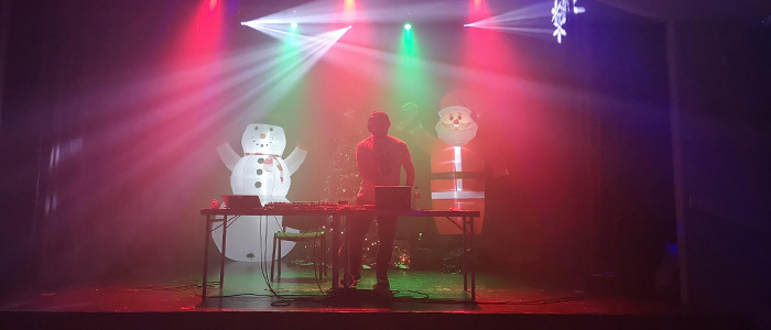 DJ på scen med uppblåsbar snögubbe och tomte.